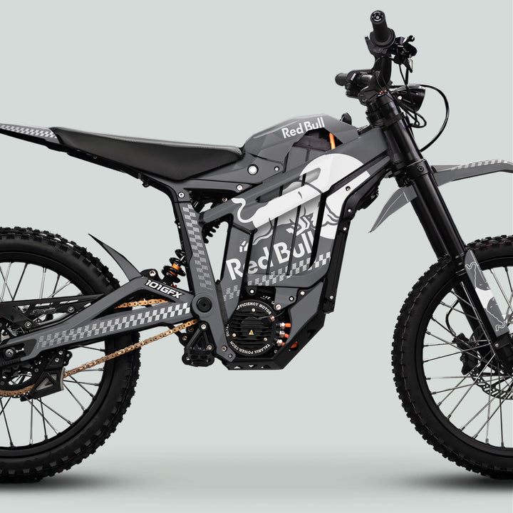 Talaria Sting MX5 PRO Graphics Kit RBULL MONO Grey White Decals on an off-road e-motocross bike with Red Bull branding, chunky tires, and electric components.