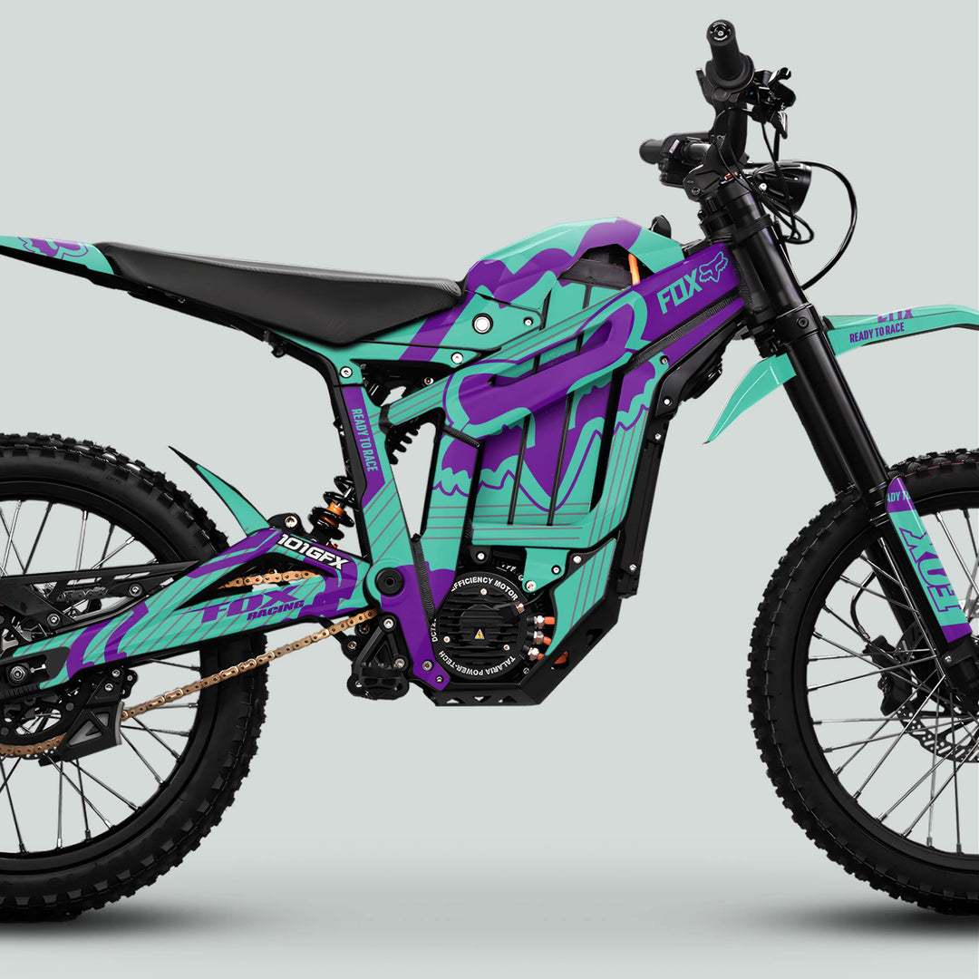 Talaria Sting MX5 PRO Graphics Kit FOX STRIPES on electric dirt bike, showcasing teal-purple Fox Racing wrap, full suspension, knobby tires, and chain drive.