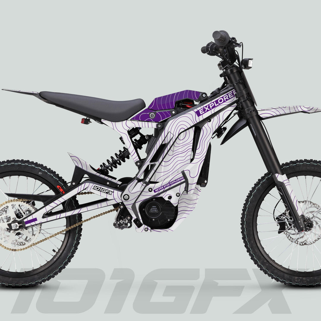Side-view of E Ride Pro SS Graphics Kit EXPLORER White Purple on an off-road e-dirt bike with high-rise handlebar, coil shock, and knobby tires.