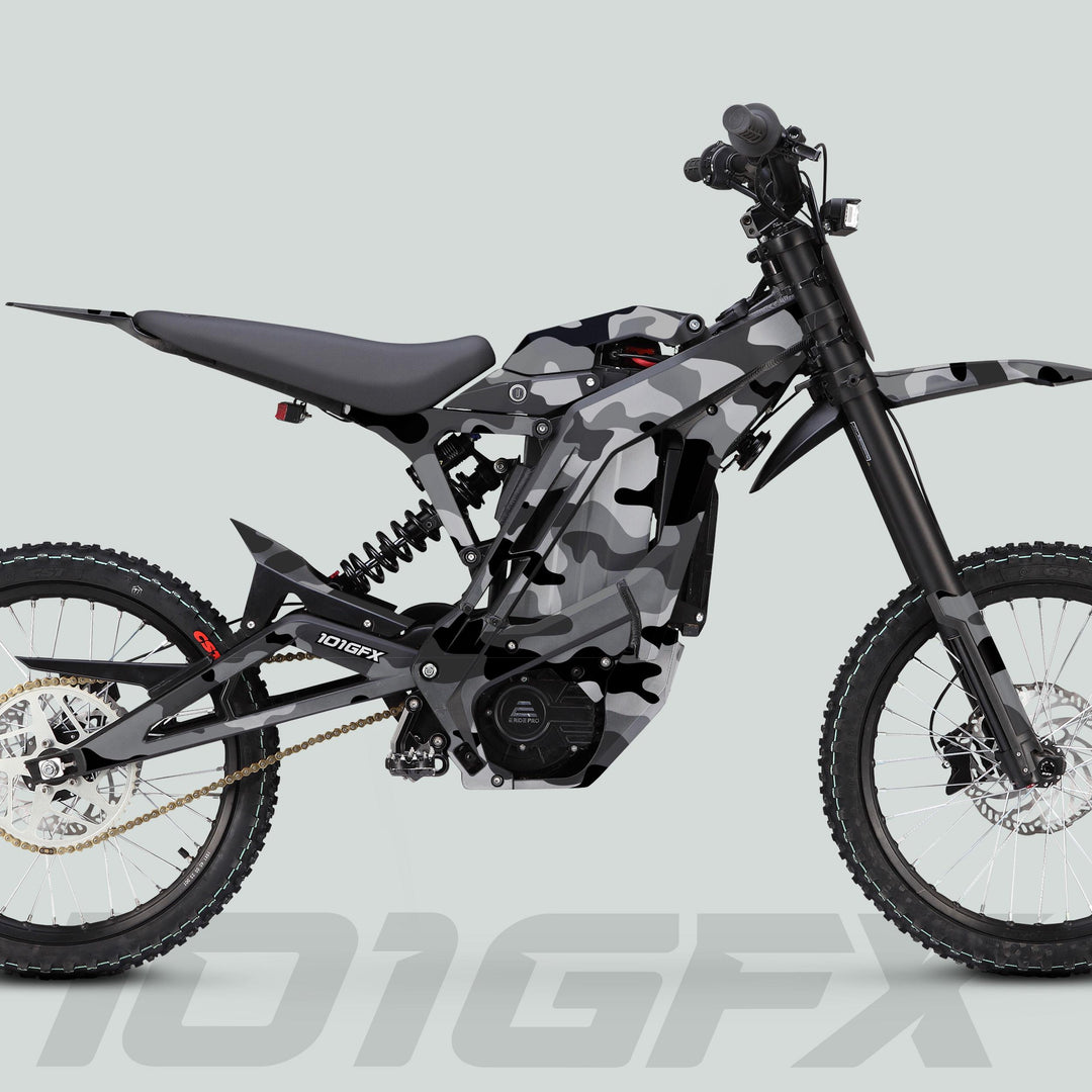 E Ride Pro SS Graphics Kit CAMOUFLAGE SNOW on an electric dirt bike, showcasing its camouflage wrap, full suspension, knobby tires, and visible battery and motor.