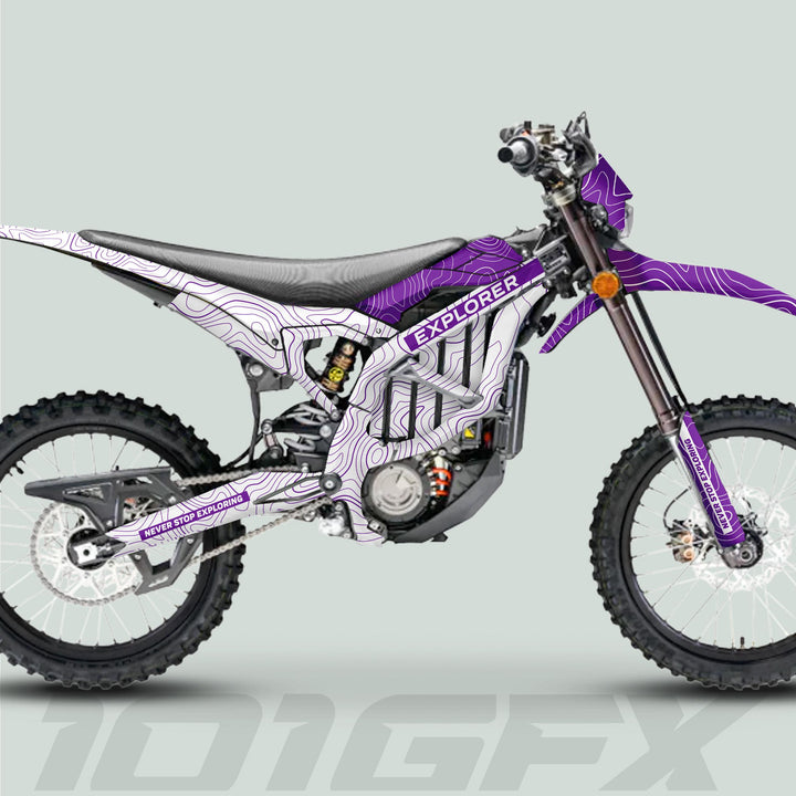 Surron Ultra Bee Graphics Kit EXPLORER WHITE PURPLE on electric enduro bike, featuring topographic map pattern, knobby tires, visible motor, and disc brakes.