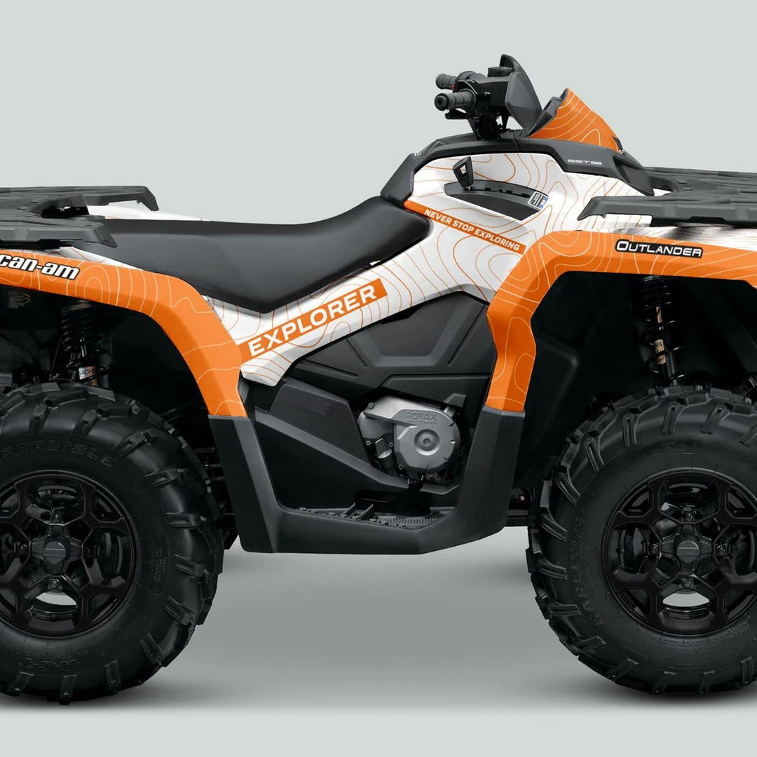 Side-profile of Can-Am OUTLANDER G2 Graphics Kit EXPLORER White Orange on an ATV, showcasing topographic wrap, chunky tires, and Rotax engine beneath the seat.