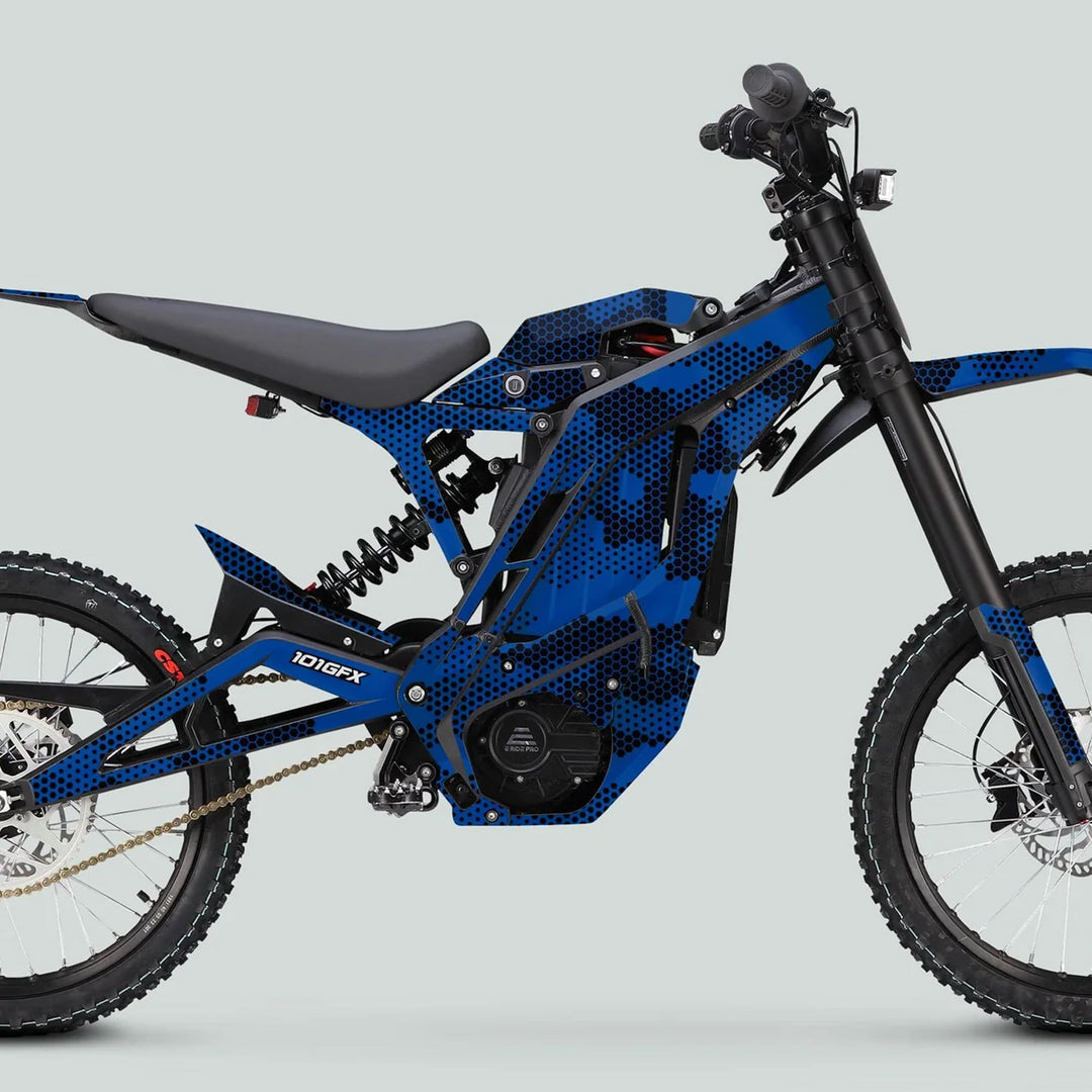 Side view of an E Ride Pro SS with HEXOCAM BLUE graphics, featuring a tubular frame, mid-mounted electric motor, suspension, knobby tires, and bicycle-style pedals.