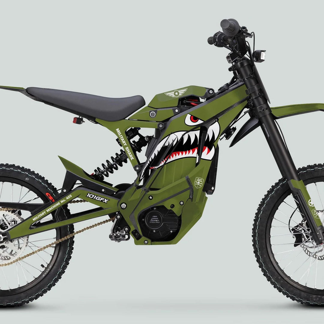 Green off-road electric dirt bike with Military Shark Olive Black graphics, featuring knobby tires, suspension forks, central battery, and MTB-style saddle.
