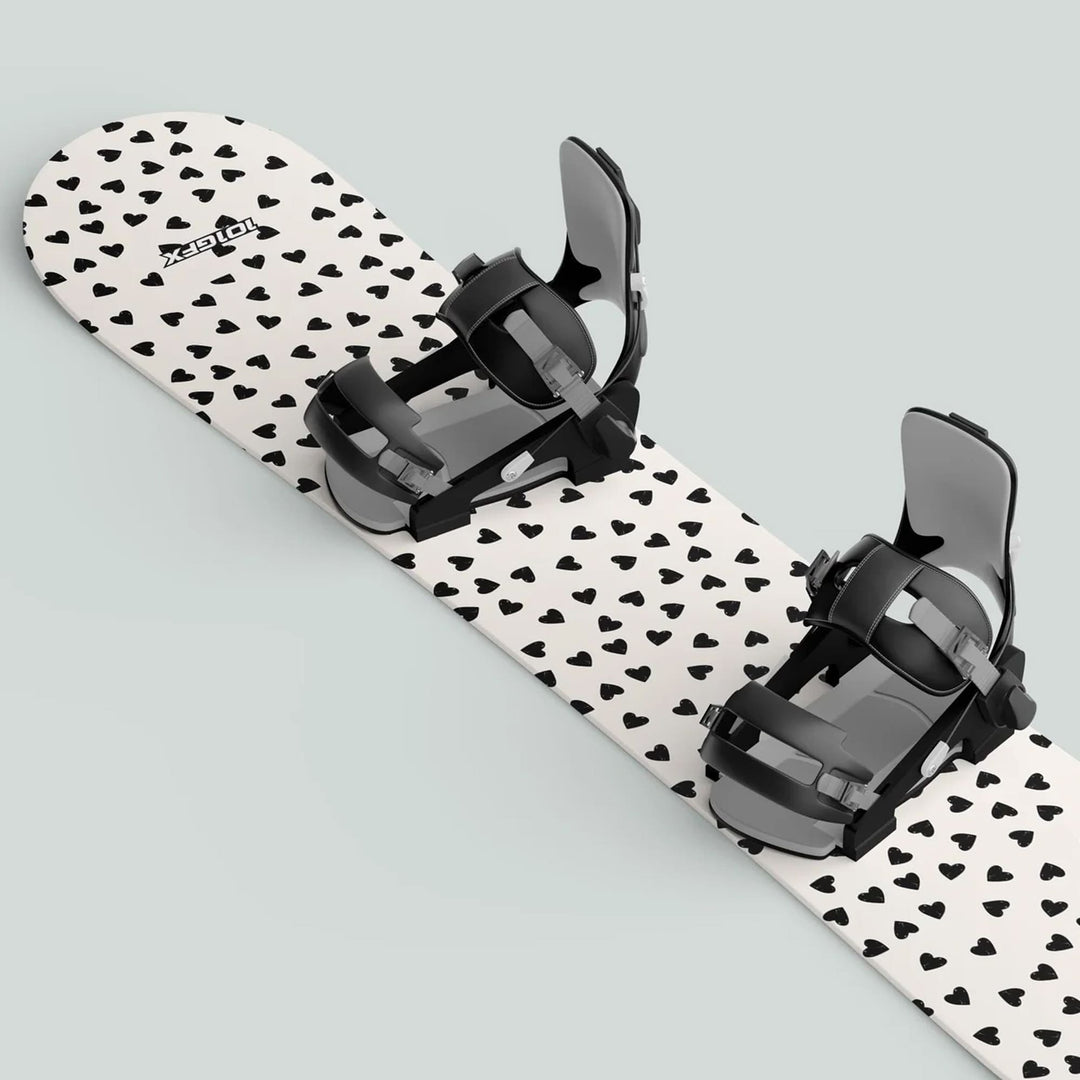 Snowboard with Snowboard Wrap HEARTS sticker skin decals, featuring black hearts pattern and mounted black-and-gray bindings for secure boot placement.