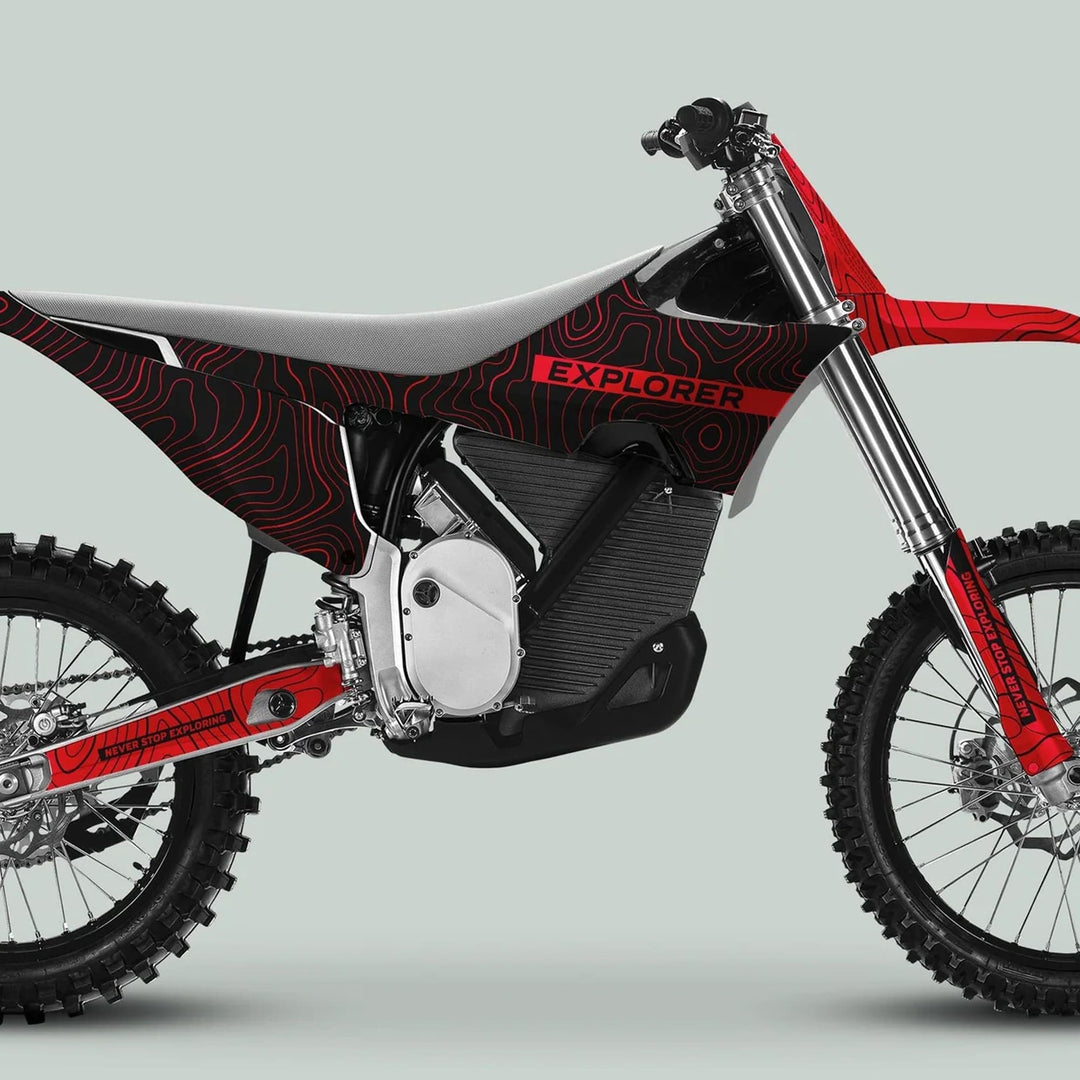 Right-side view of a dirt bike featuring the Stark Varg Graphics Kit with EXPLORER theme decals on a central housing, knobby tires, and advanced suspension.