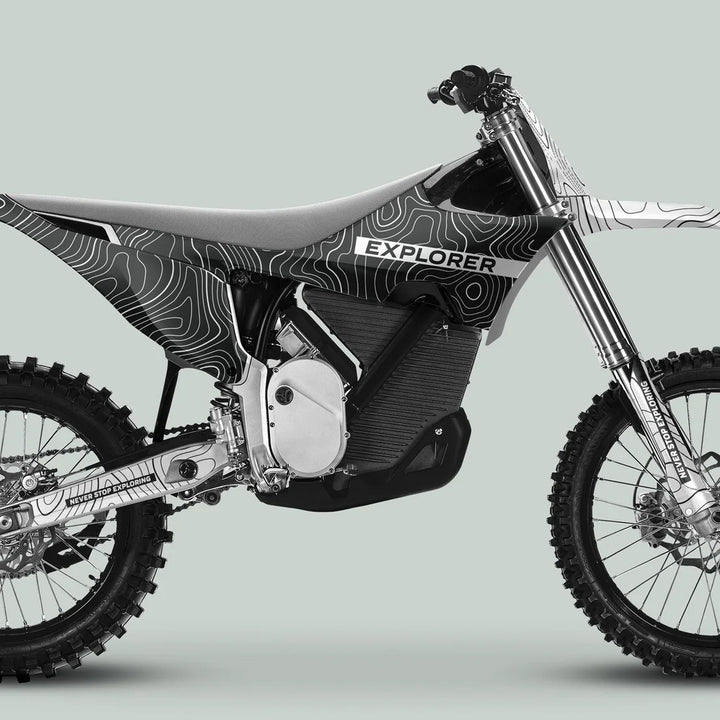 Side-view of an electric dirt bike with Stark Varg Graphics Kit EXPLORER GREY WHITE, featuring a topographic graphic wrap and branded with Never Stop Exploring.