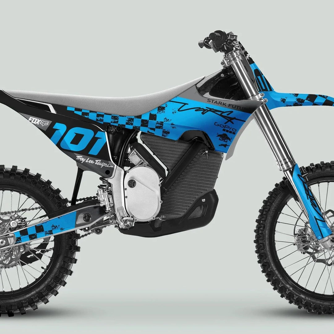 Side-profile of a blue electric dirt bike with Stark Varg Graphics Kit RACE BLACK Cyan Decals featuring knobby tires, inverted forks, and sponsor logos.
