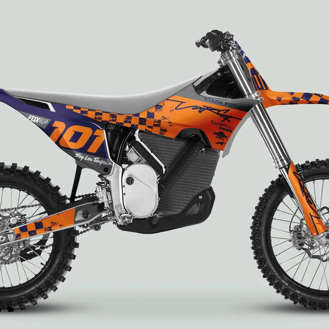 Stark Varg Graphics Kit RACE NAVY Orange Decals on an electric motocross bike with knobby tires, showcasing branding like 101, Troy Lee Designs, and Fox.