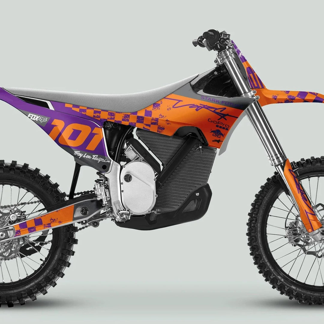 Side profile of an off-road motocross bike featuring Stark Varg Graphics Kit RACE PURPLE Orange Decals Stickers, showcasing knobby tires, slim seat, and branded accents.