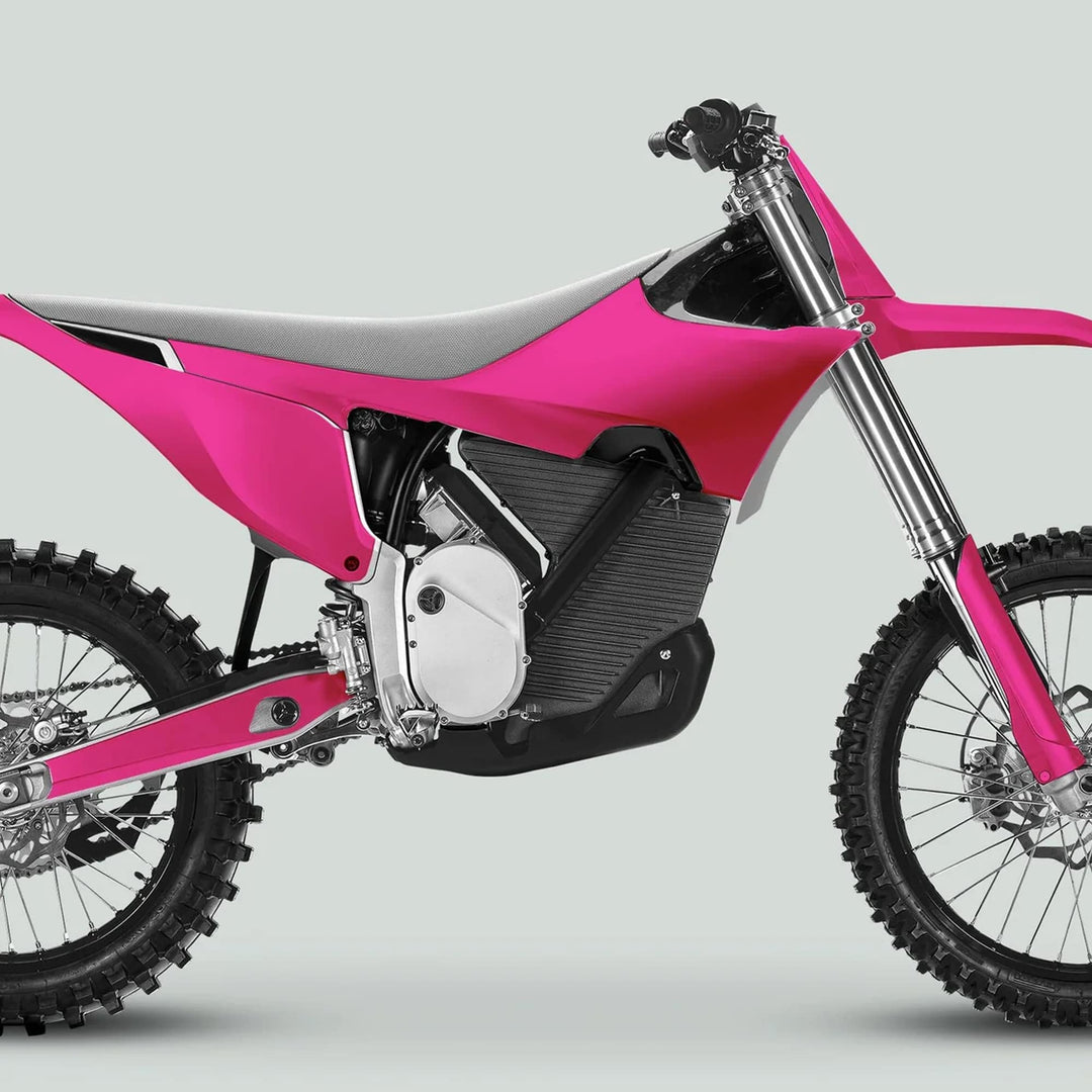 Side view of an electric motocross bike with Stark Varg Graphics Kit SOLID COLOR MAGENTA, featuring knobby tires and telescopic forks against a light-gray backdrop.