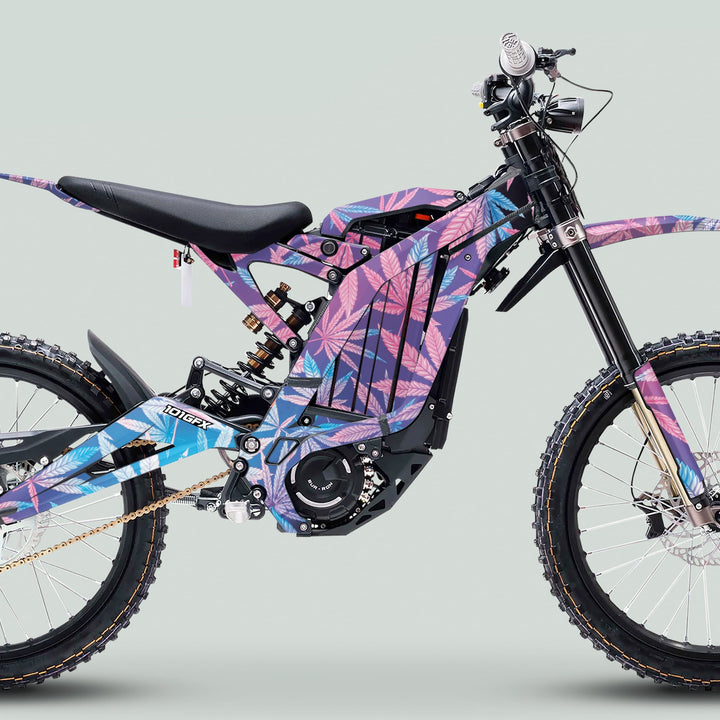 Side-profile of an electric dirt bike with Surron Light Bee X Graphics Kit 420 CANNABIS Glow, featuring colorful leaf decals and branded motor cover.