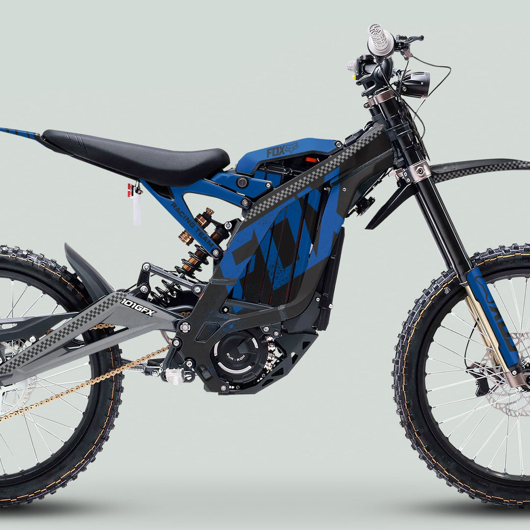 Surron Light Bee X Graphics Kit FOX DUST Black Blue on an electric dirt-bike side profile, showcasing knobby tires, sleek frame, and durable, stylish decals.