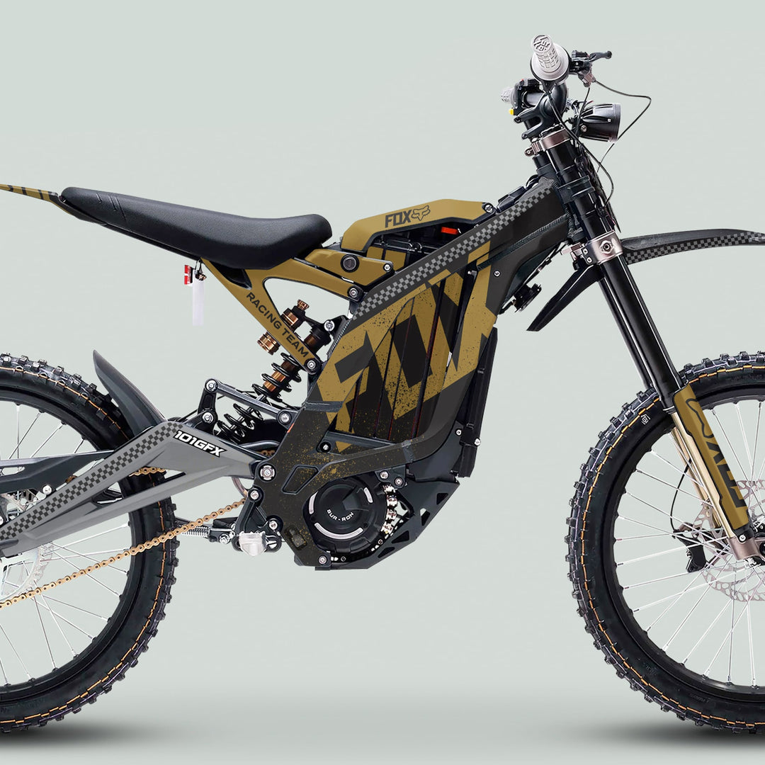 Surron Light Bee X Graphics Kit FOX DUST Black Gold on an electric off-road bike with a large battery, mid-drive motor, full suspension, and knobby tires.