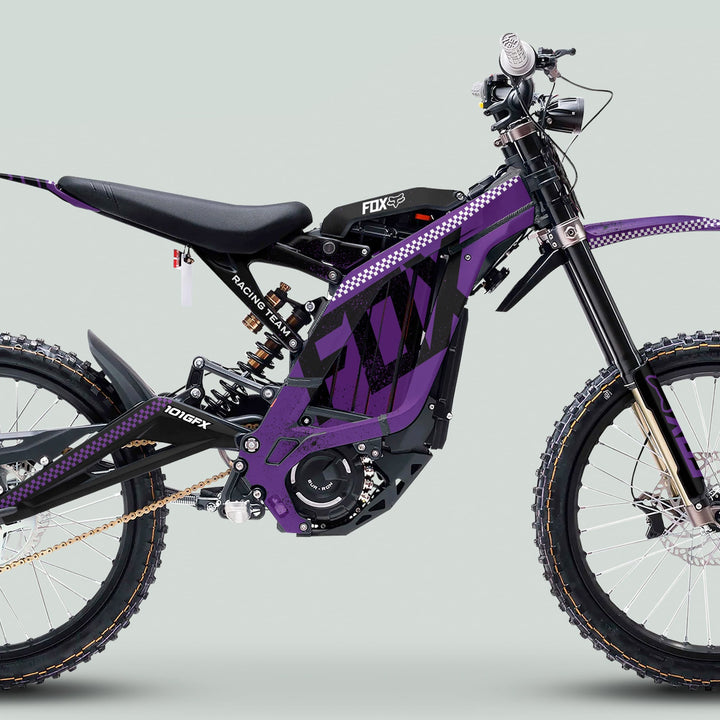Side profile of a Surron Light Bee X with the Graphics Kit FOX DUST Purple Black, featuring durable decals, knobby tires, and long-travel suspension.