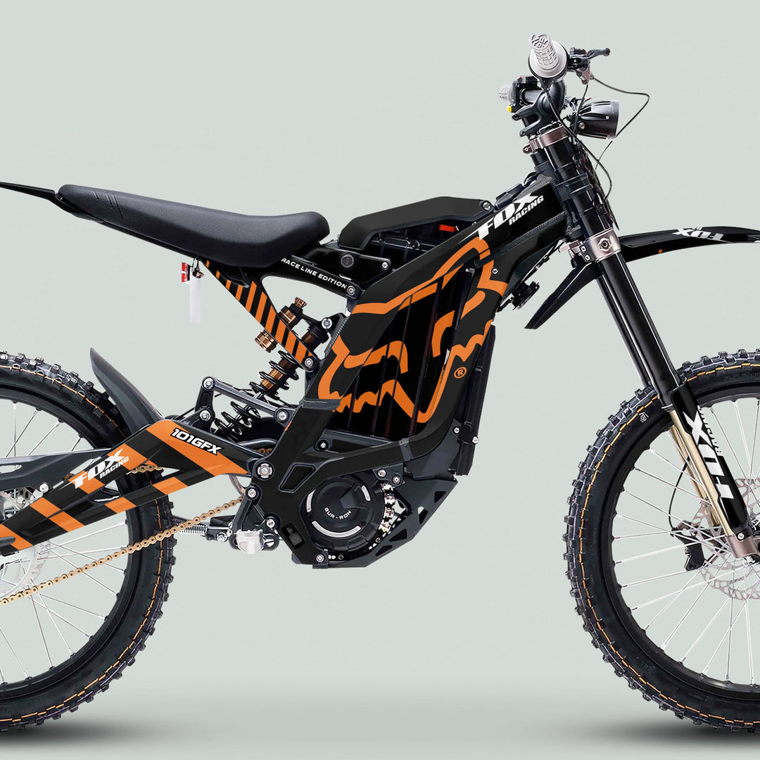 Surron Light Bee X Graphics Kit FOX RACE LINE Black Orange on an e-trail bike with knobby tires, coil shock, and motocross-style saddle.