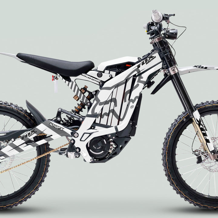 Surron Light Bee X Graphics Kit FOX RACE LINE White Grey on e-dirt bike with chunky tires, gold chain, electric motor, and long-travel forks enhances off-road style.