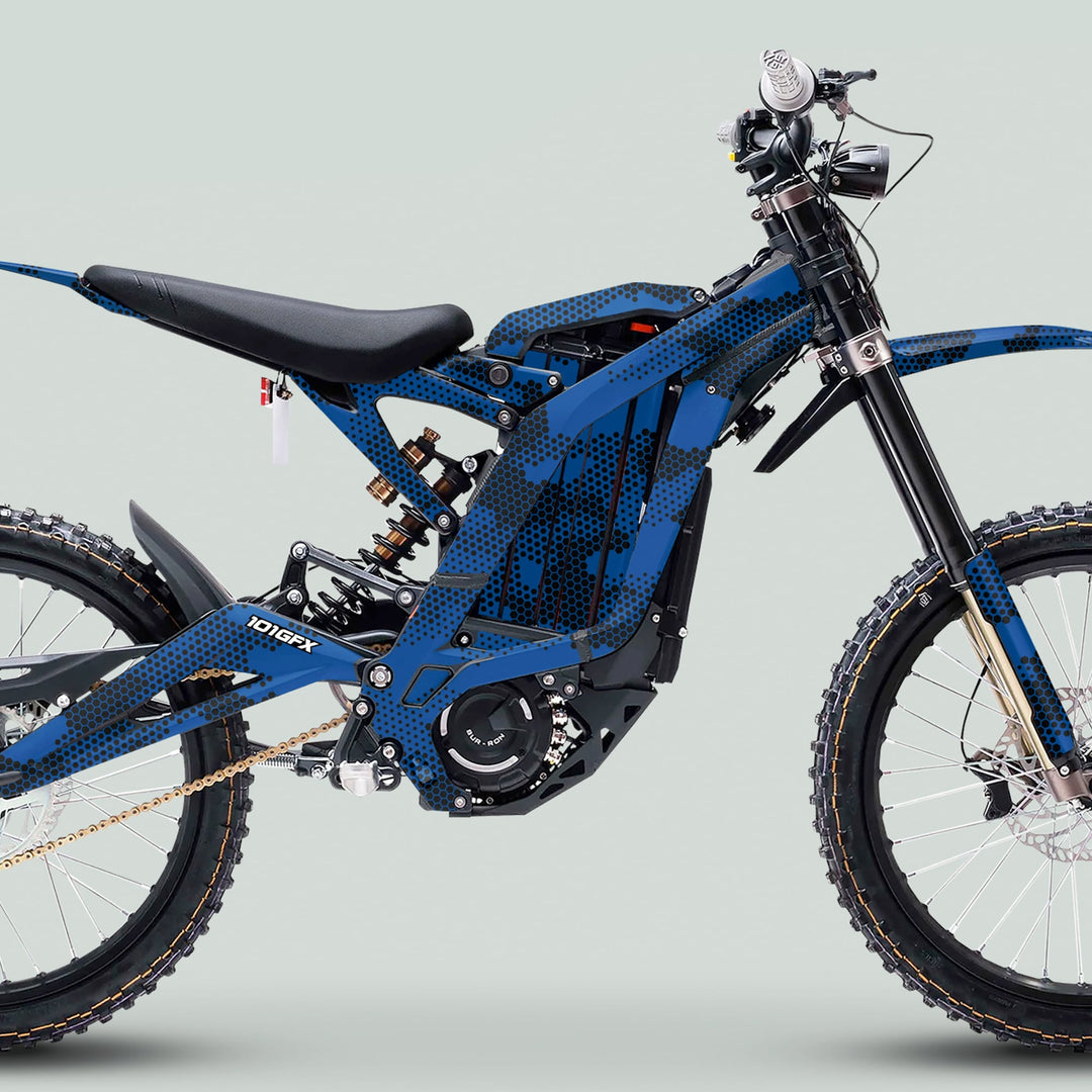 Side profile of a blue Surron Light Bee X e-motorcycle featuring the HEXOCAM Blue Graphics Kit, showcasing tubular frame, padded seat, and off-road components.