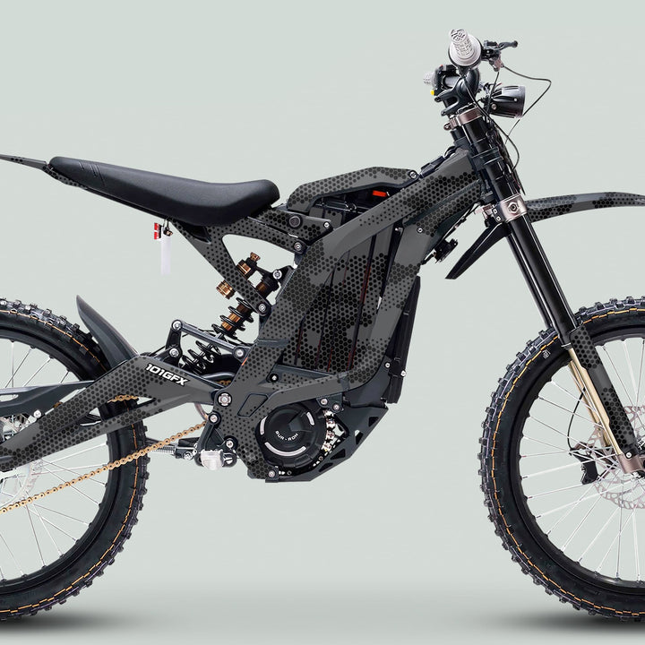 Electric dirt bike with Surron Light Bee X Graphics Kit HEXOCAM Grey, showcasing a honeycomb camo pattern, electric hub-motor, long-travel suspension, and off-road tires.