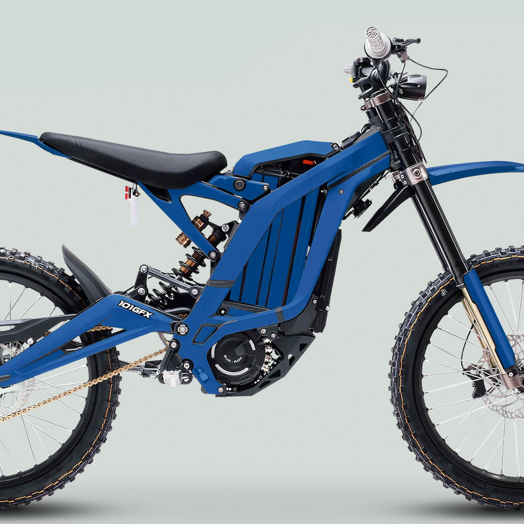 Side-view of a blue electric off-road bike featuring the Surron Light Bee X Graphics Kit MONO COLOR Blue, showcasing knobby tires, suspension, and motor housing.