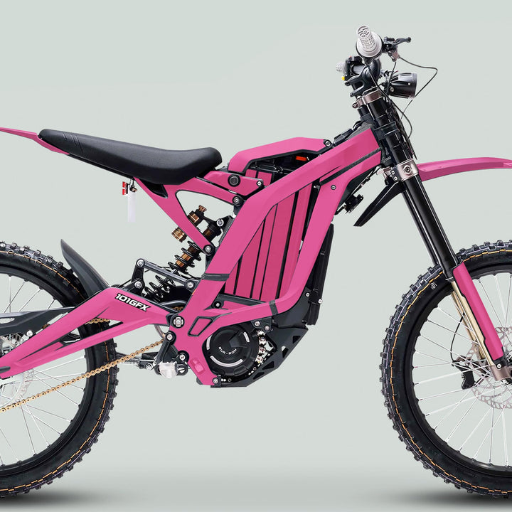 Surron Light Bee X Graphics Kit MONO COLOR Pink on an electric dirt bike, showcasing full suspension, knobby tires, and handlebar controls.