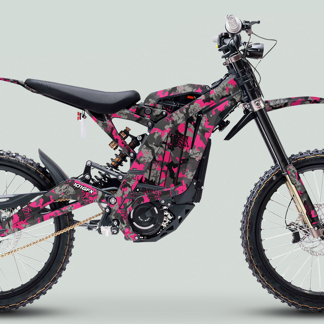 Side profile of an e-dirt bike with the Surron Light Bee X Graphics Kit SPLAT CAMO Purple, showcasing its unique pink, gray, and black camouflage wrap.