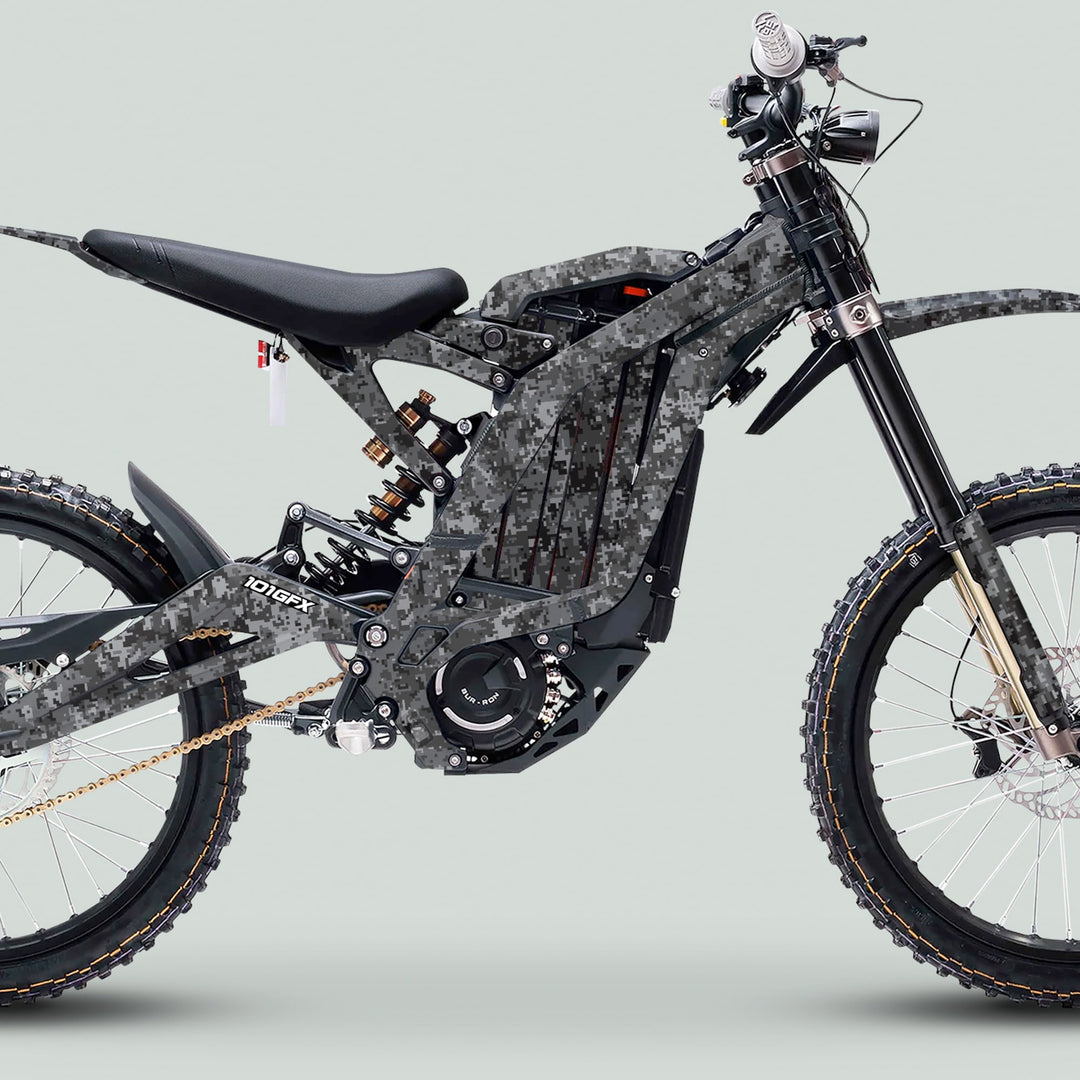 Surron Light Bee X Graphics Kit SQUARE TEK grey on a camo-patterned electric dirt bike, featuring full suspension and knobby tires, enhancing bike aesthetics and protection.