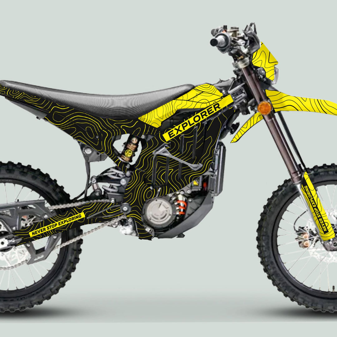 Side-view of a dirt bike with Surron Ultra Bee Graphics Kit EXPLORER BLACK YELLOW, featuring yellow contour-line patterns and NEVER STOP EXPLORING slogan.