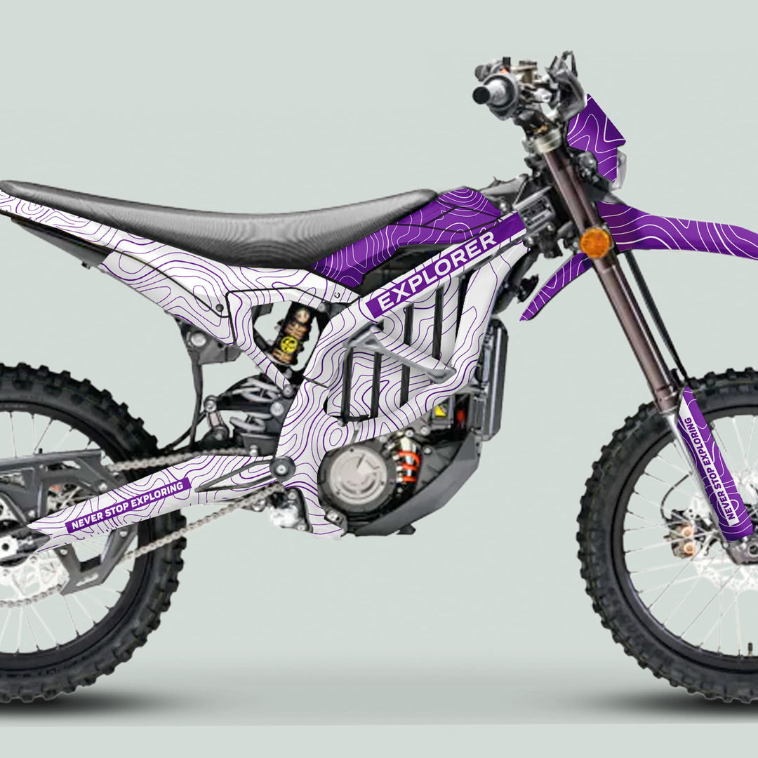 Side-profile of a motocross bike with Surron Ultra Bee Graphics Kit EXPLORER WHITE PURPLE, featuring topographic-line design and NEVER STOP EXPLORING text on parts.
