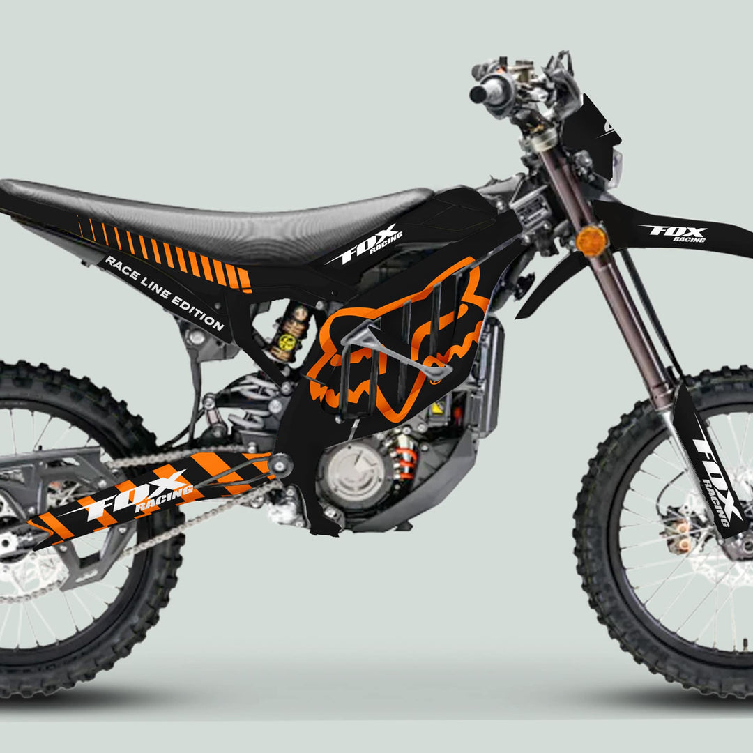 Side view of Surron Ultra Bee Graphics Kit FOX RACE LINE Black Orange on a dirt bike, featuring custom black plastics with orange Fox logos and white text.
