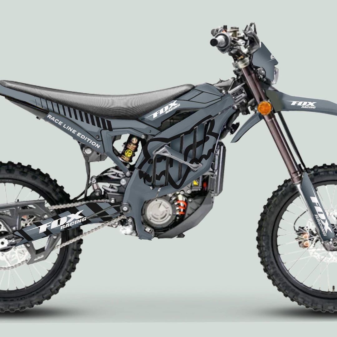 Side-profile of a motocross bike in gray FOX RACE LINE livery, showcasing the Surron Ultra Bee Graphics Kit's sleek, durable design with knobby tires and disc brakes.