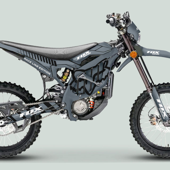 Side-profile of a motocross bike in gray FOX RACE LINE livery, showcasing the Surron Ultra Bee Graphics Kit's sleek, durable design with knobby tires and disc brakes.