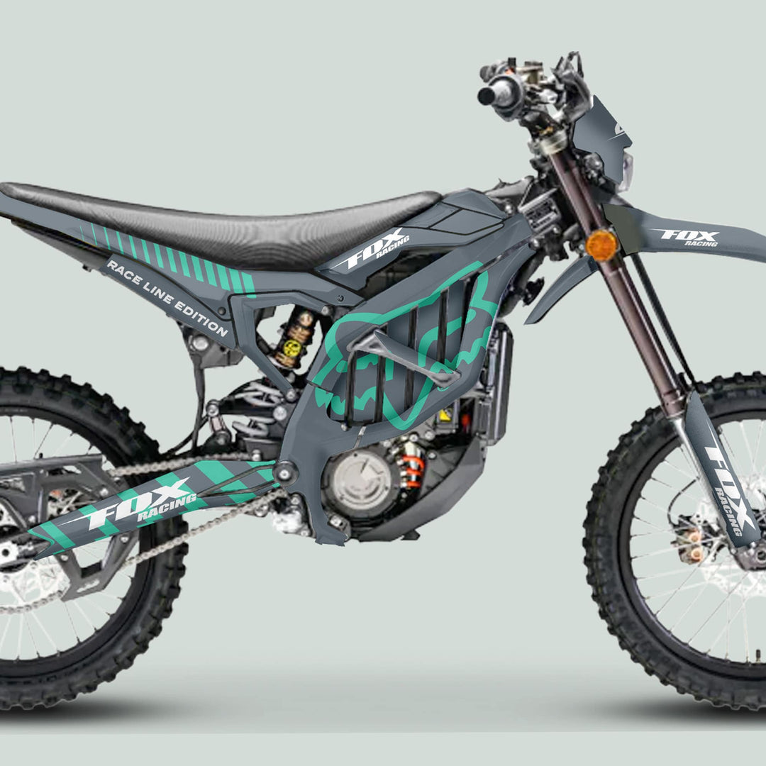 Side-view of a dirt bike with the Surron Ultra Bee Graphics Kit FOX RACE LINE Grey Mint, featuring Fox Racing logos and off-road components.