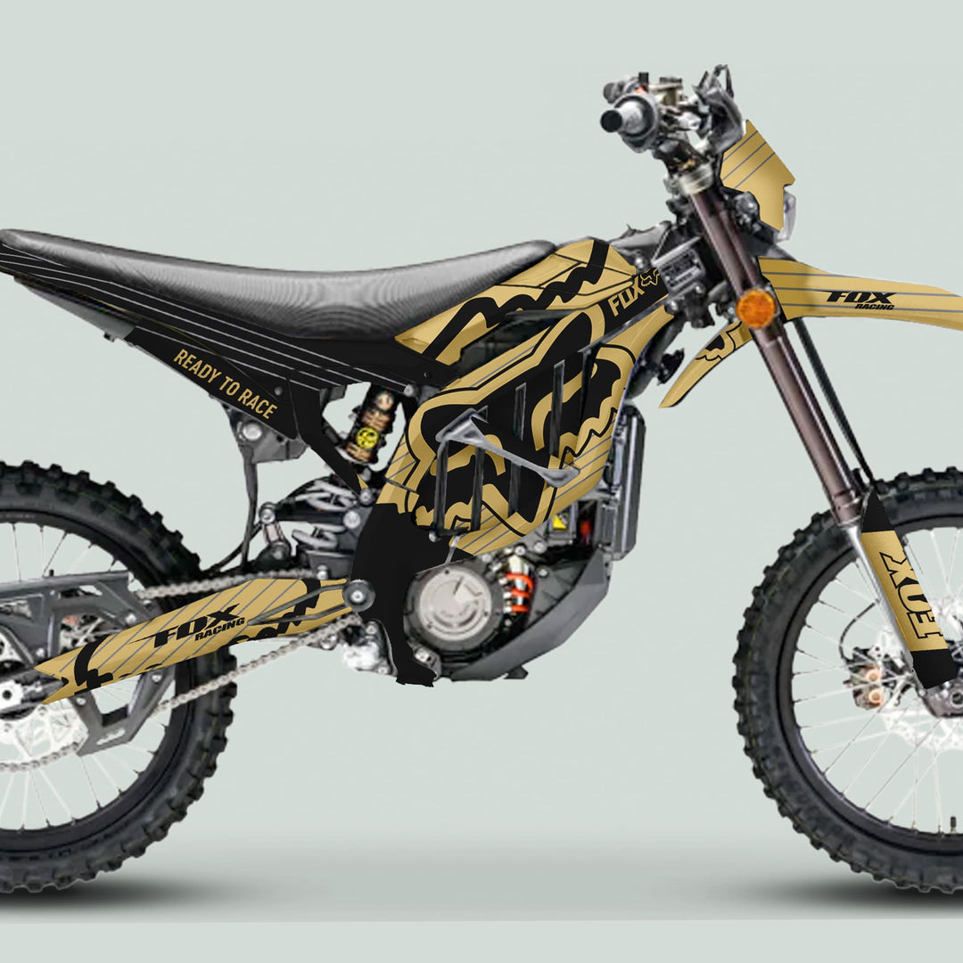 Motocross dirt bike with Surron Ultra Bee Graphics Kit FOX STRIPES Sand Black, featuring gold-and-black Fox Racing design, READY TO RACE decal, and durable styling enhancements.