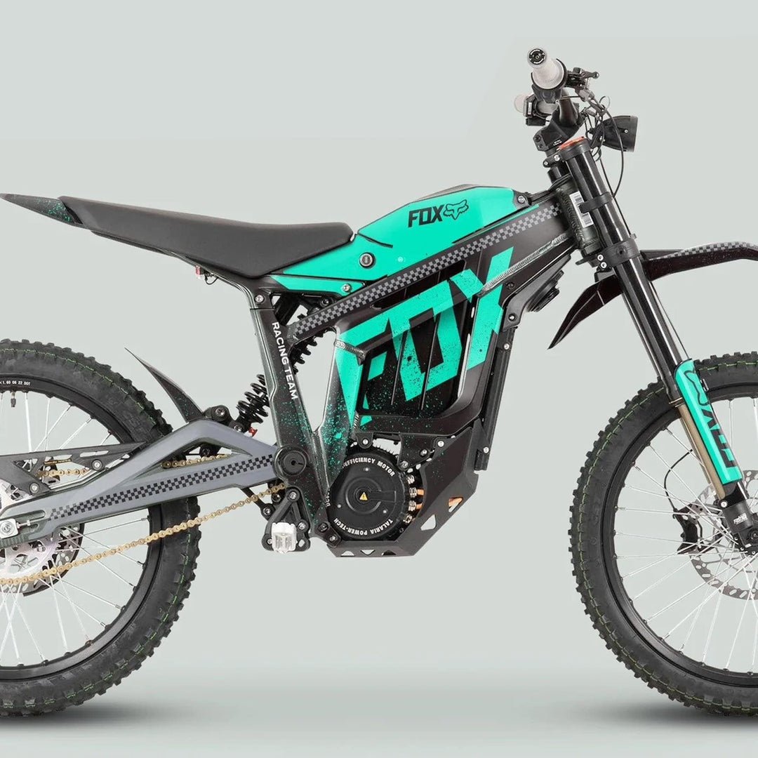 Side view of Talaria Sting MX3 MX4 Graphics Kit FOX DUST Black Mint on an off-road electric dirt bike, showcasing knobby tires and teal-and-black racing graphics.