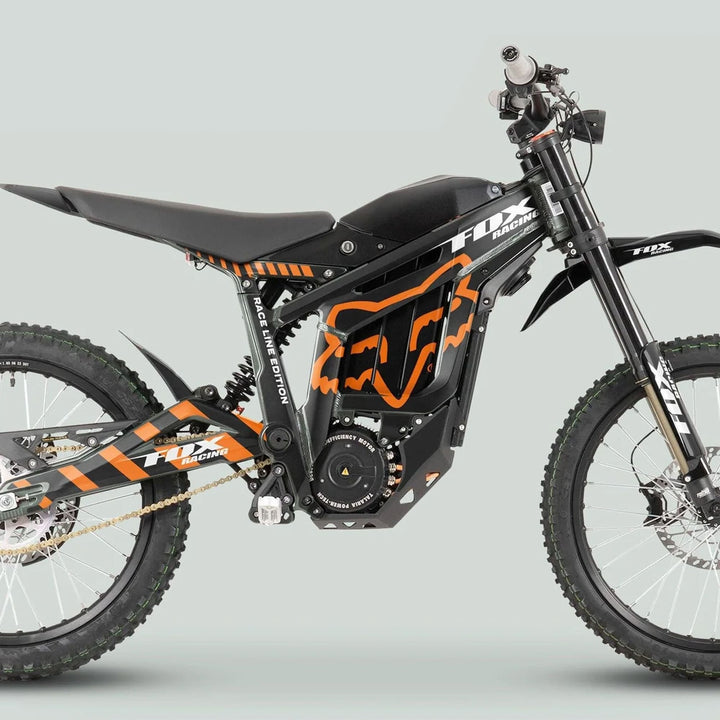 Side view of a Fox Racing-branded Talaria Sting MX3 MX4 Graphics Kit, showcasing black and orange design with knobby tires and dual suspension.