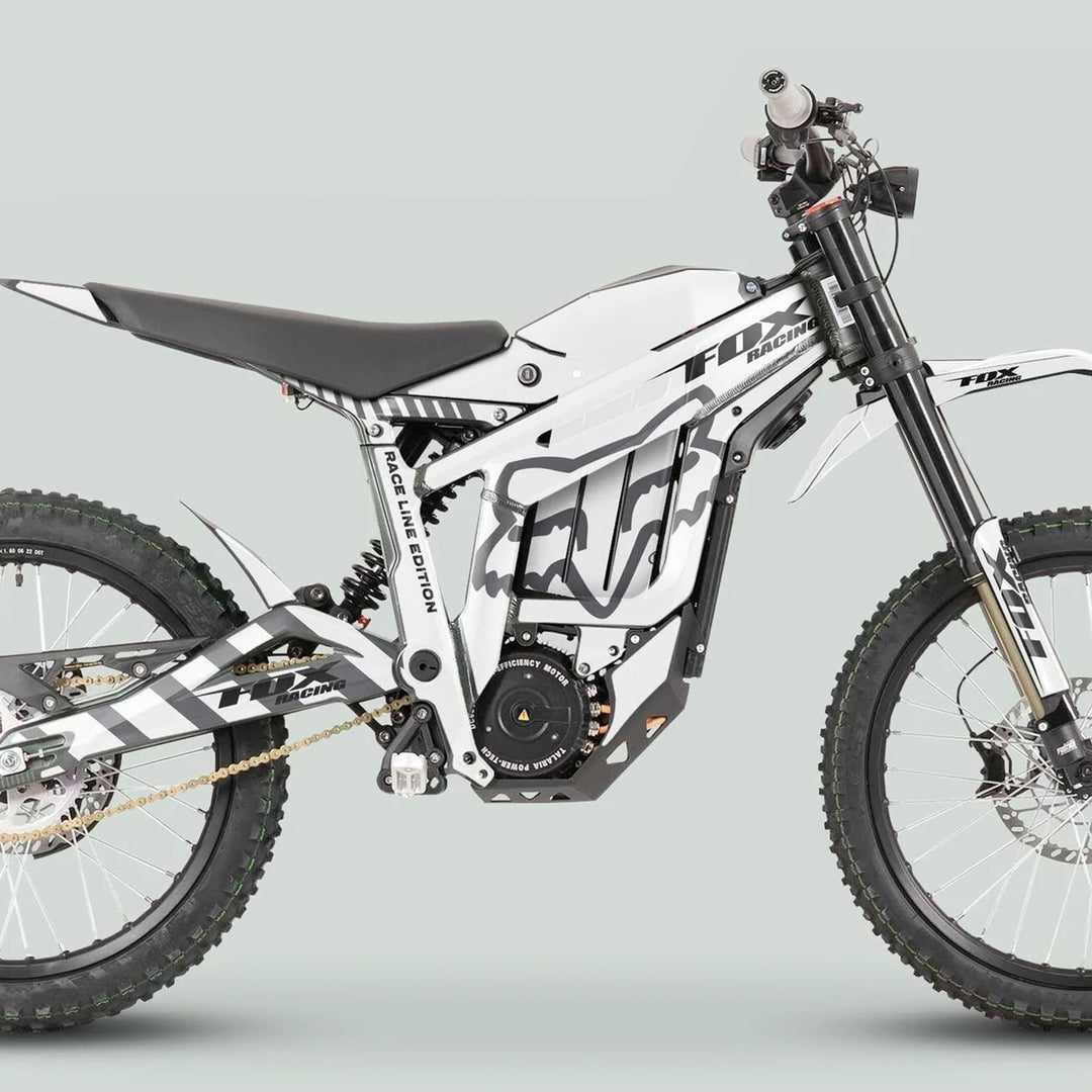 Side-profile of a white off-road e-motorcycle with Talaria Sting MX3 MX4 Graphics Kit FOX Raceline White Grey, featuring knobby tires and sleek design.