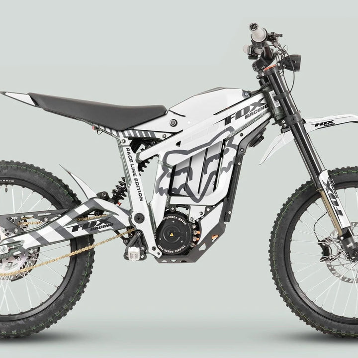 Side-profile of a white off-road e-motorcycle with Talaria Sting MX3 MX4 Graphics Kit FOX Raceline White Grey, featuring knobby tires and sleek design.