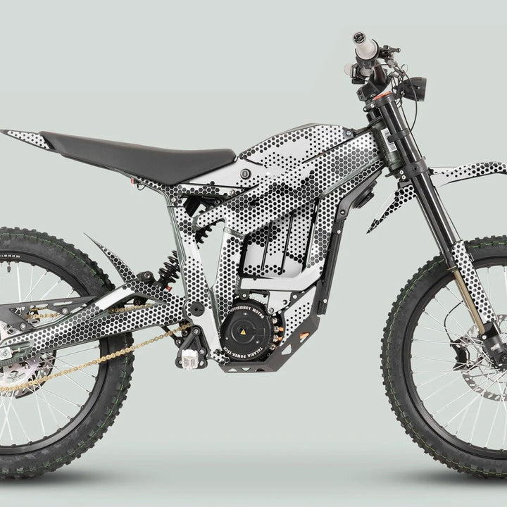 Side profile of an electric dirt bike with Talaria Sting MX3 MX4 Graphics Kit HEXOCAM White, featuring knobby wheels, long-travel suspension, and camo-style wrap.
