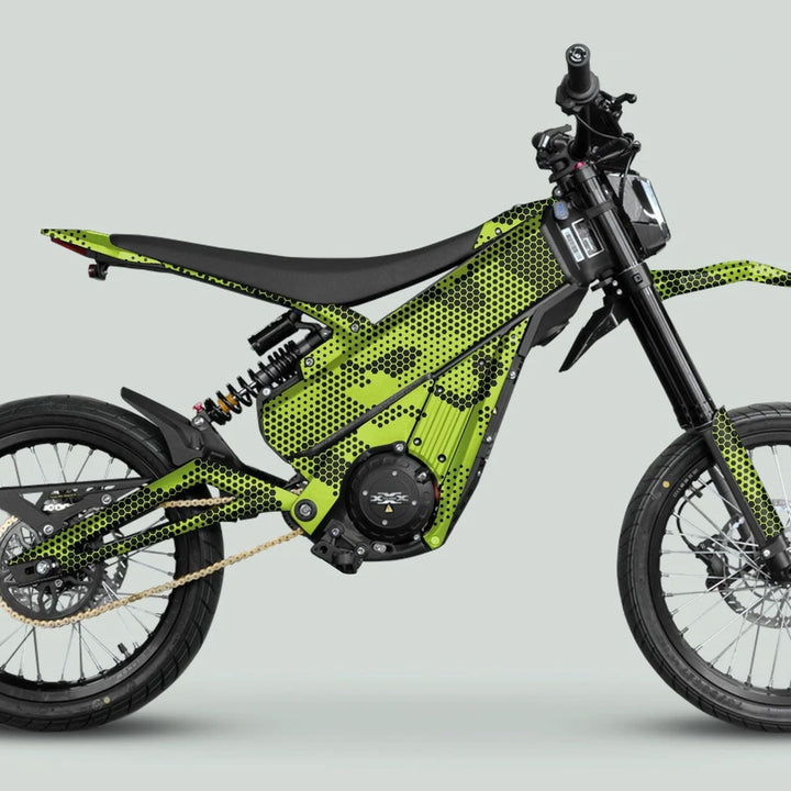 Side-view of a Talaria e-dirt bike with HEXOCAM Green graphics, featuring a high-torque electric motor, knobby tires, and angular green-black honeycomb frame.