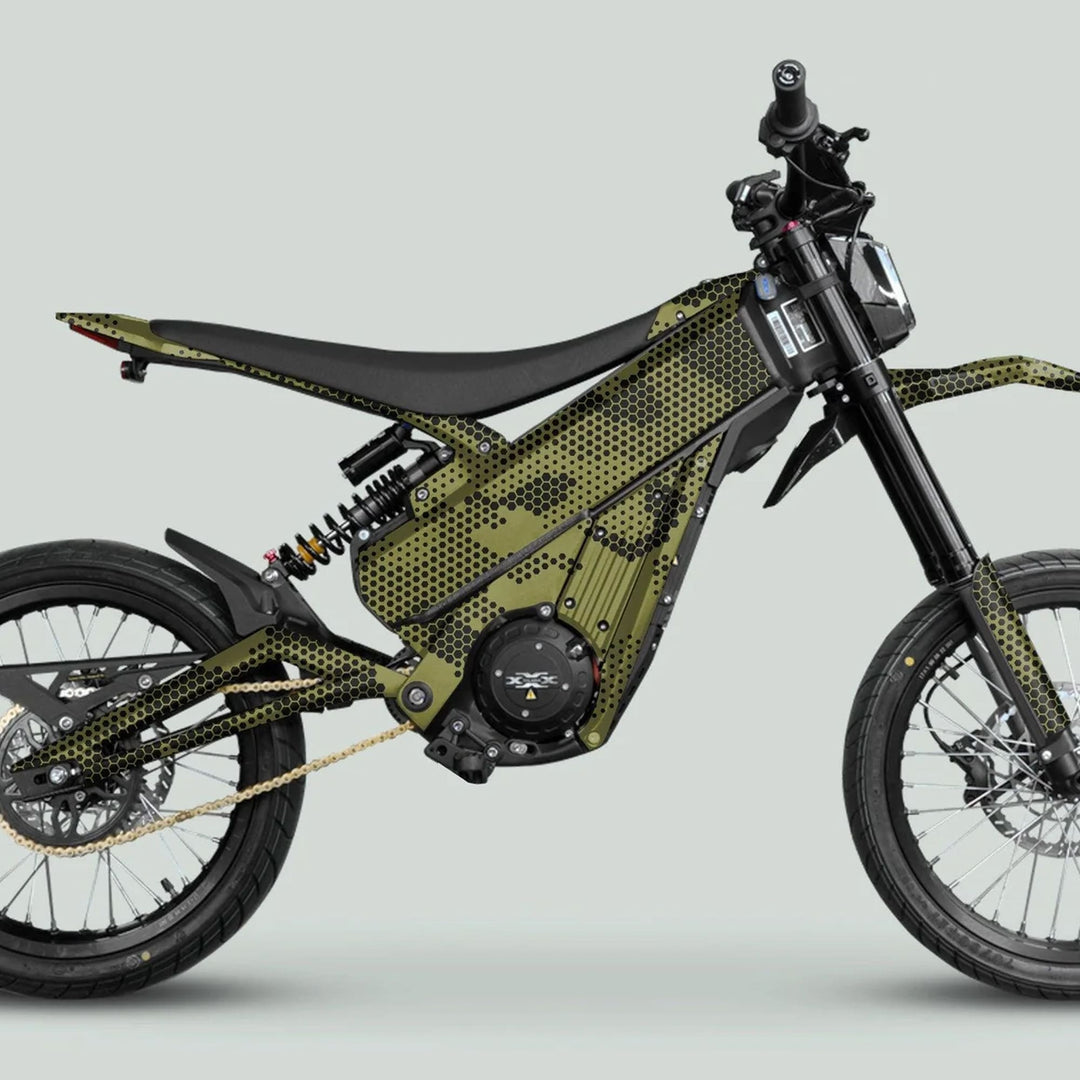 Electric off-road motorcycle with Talaria XXX Graphics Kit HEXOCAM Olive, featuring a honeycomb camo wrap on central housing, spoked wheels, and gold chain.